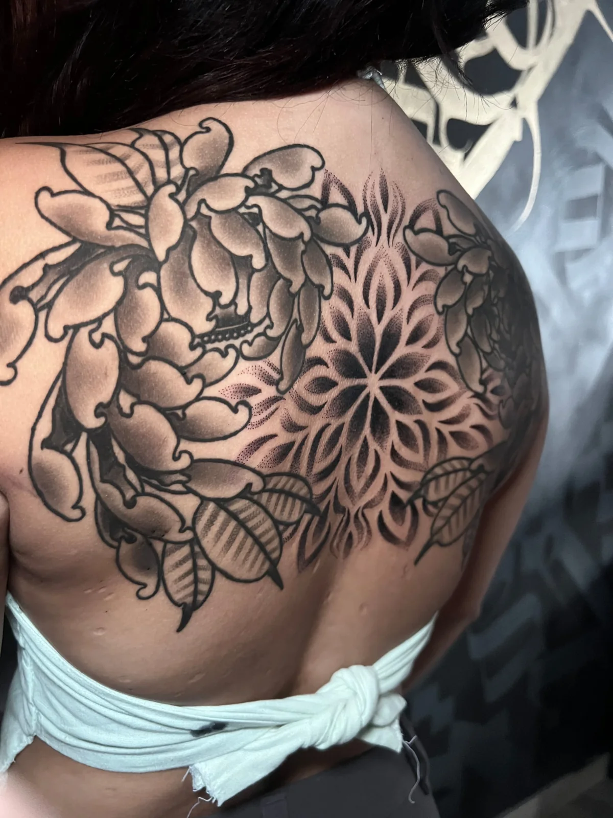 Gran pieza en la espalda que combina peonías y mandala en blackwork ornamental